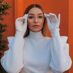a woman wearing glasses while holding her hand on the forehead