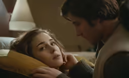 a man and woman laying next to each other on a bed