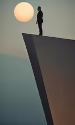 a man is standing on a ledge that has an unusual shape in the sky
