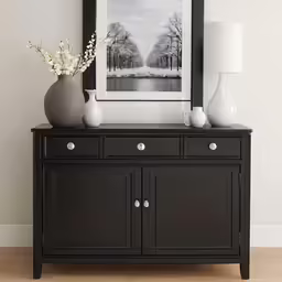 a black crede cabinet has three vases on it