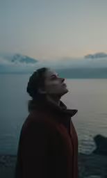 a woman is standing near the water and looking up