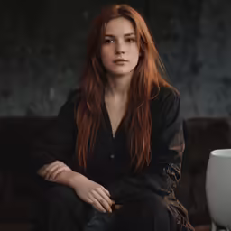 a woman with red hair sitting on a brown couch