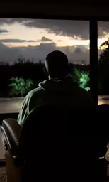 a man is sitting down watching a sunset