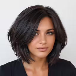 a young woman with dark hair, wearing a black top and posing for the camera