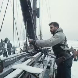 a man standing on the back of a boat in the snow