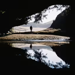 the silhouette of a man standing near a lake in the dark