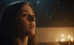 a girl looking at a candle lit room
