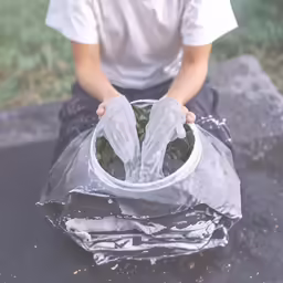 young boy placing a plastic bag on an outdoor table