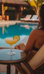 a woman sitting next to a table near a swimming pool