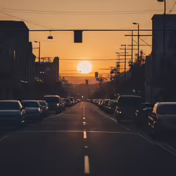 a street lined with cars during sunset near an intersection