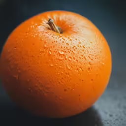 there is an orange on the table covered in drops of water