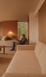 a man is sitting on the couch using a laptop