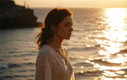 a woman standing by the sea at sunset