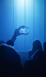 people sitting down with their hands in the air and one hand holding onto a light bulb