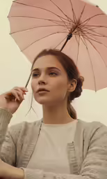 a young woman standing under an umbrella and holding the tip of her nose