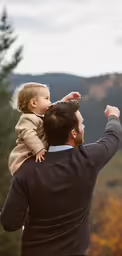 the man is holding up a little girl in his arms