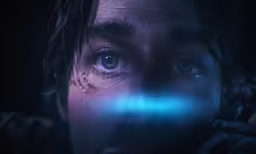 a young person with blue eyes and a blue light behind him