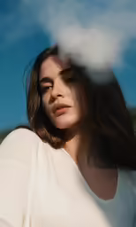 a young lady looks at the camera while blowing smoke