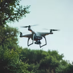 a flying white quad propellers camera system hovering over trees
