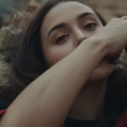 a woman laying on a ledge with her eyes closed