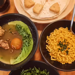 bowls of food sit on a table with utensils
