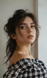 a young woman in plaid shirt posing by a window
