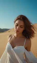 a young lady with her head down is walking across the desert