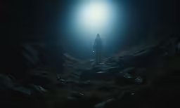 man standing in dark rocky field on foggy night