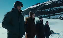people are standing in the snow near a mountain