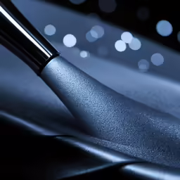 a silver brush with a black surface in the background