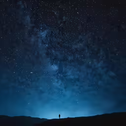 a person standing on a hill, under the stars