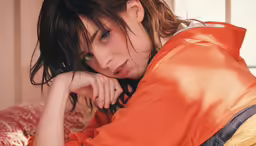a woman in an orange shirt laying down