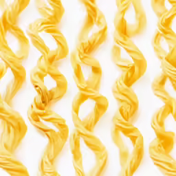 many strands of yellow colored noodles on a white surface