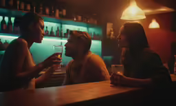three people sitting at a bar drinking and talking