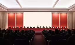 a room with two men on a stage surrounded by people