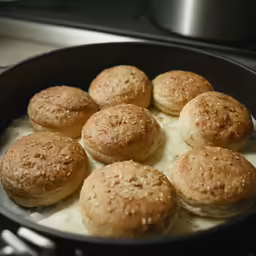 a skillet with cooked biscuits and sauce on the side