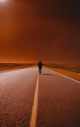 a lone man stands alone along an empty road