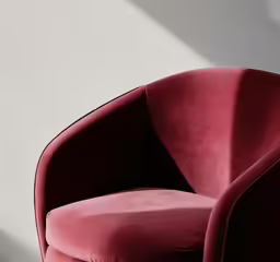 a red chair with large black seat next to a wall
