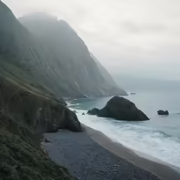 a view of a foggy beach near some mountains