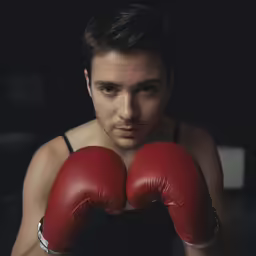 a man in a tank top is posing for a picture wearing red gloves