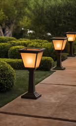the small lighted lamps are outside by the sidewalk