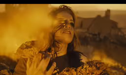 a woman standing in front of an area full of yellow fire