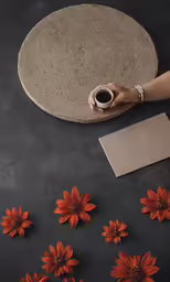 a person holding a cup over some flowers