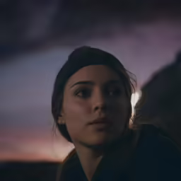 a woman staring intently at the camera while wearing a hat