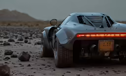 a silver race car sits on some rocks in the desert