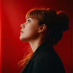 a young woman posing in front of a red background