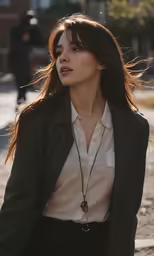 a woman in a black blazer and shirt holds a silver necklace