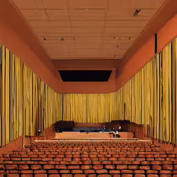 an empty auditorium is decorated in red and yellow,an auditorium filled with lots of seats facing toward a stage