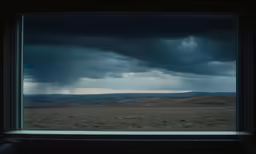 an open window with rain over the field below