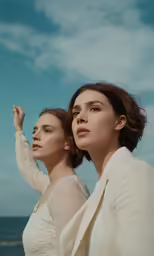 two women with white shirts and one is pointing to the sky